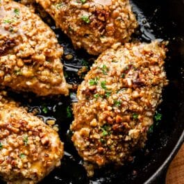 close-up of walnut crusted chicken in cast iron skillet.