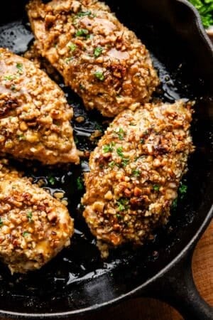 close-up of walnut crusted chicken in cast iron skillet.