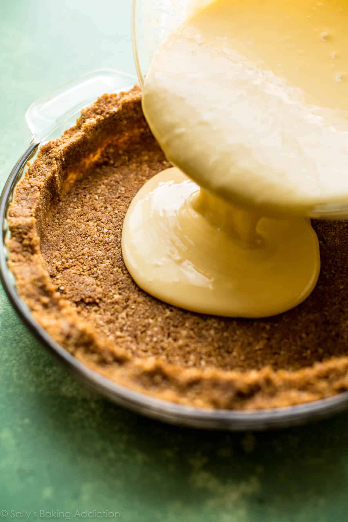 pouring key lime pie filling into graham cracker crust