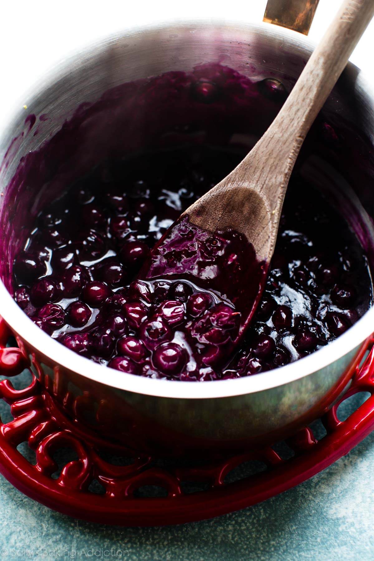 blueberry sauce in a saucepan with a wood spoon