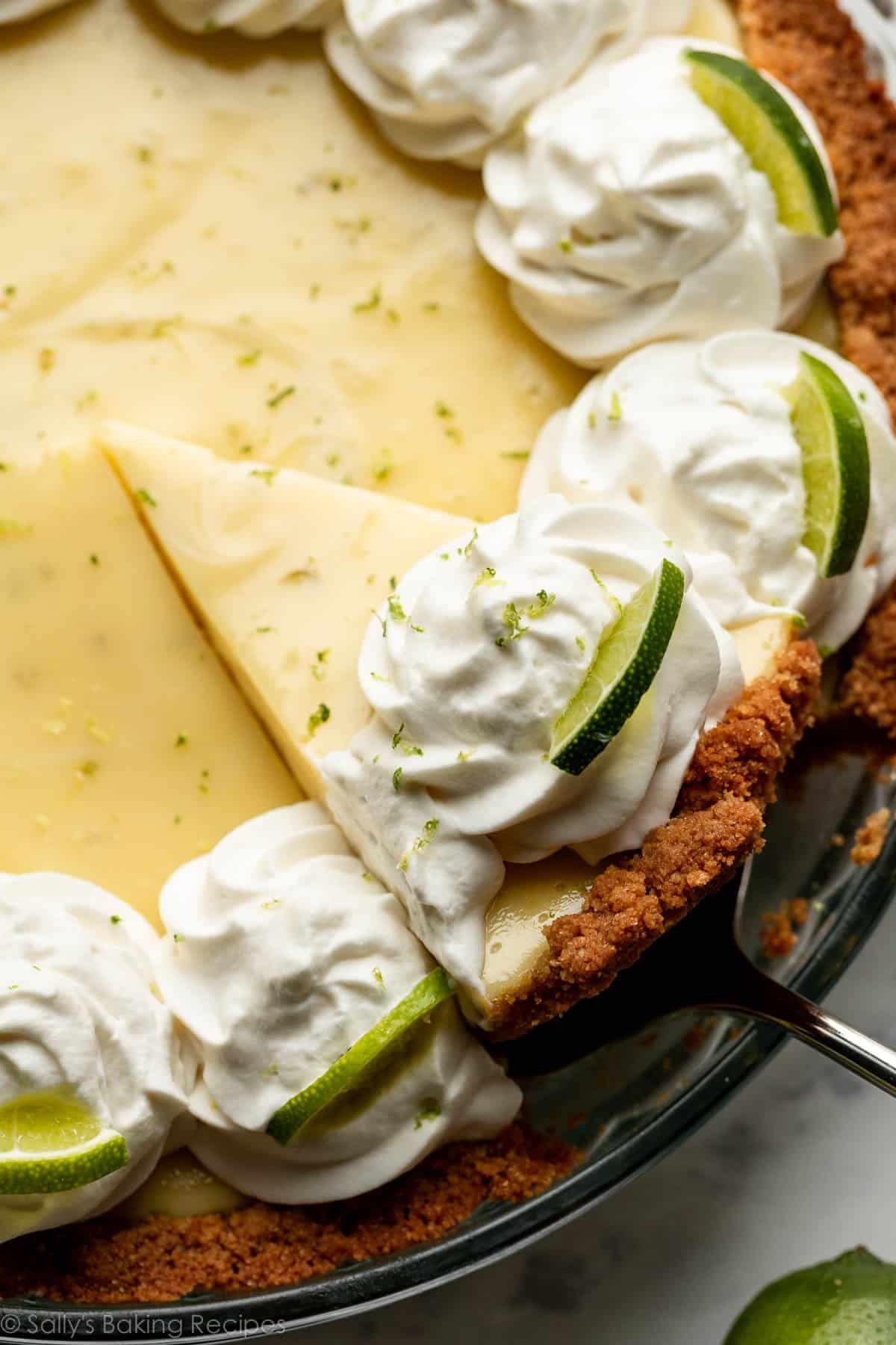 slice of key lime pie being removed from glass pie dish.