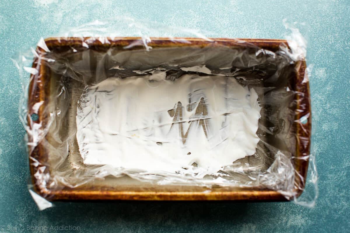 thin layer of whipped cream on the bottom of a loaf pan lined with plastic wrap