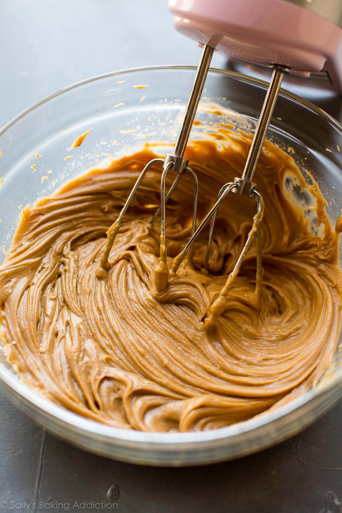 peanut butter swirl mixture in a glass bowl with a hand mixer