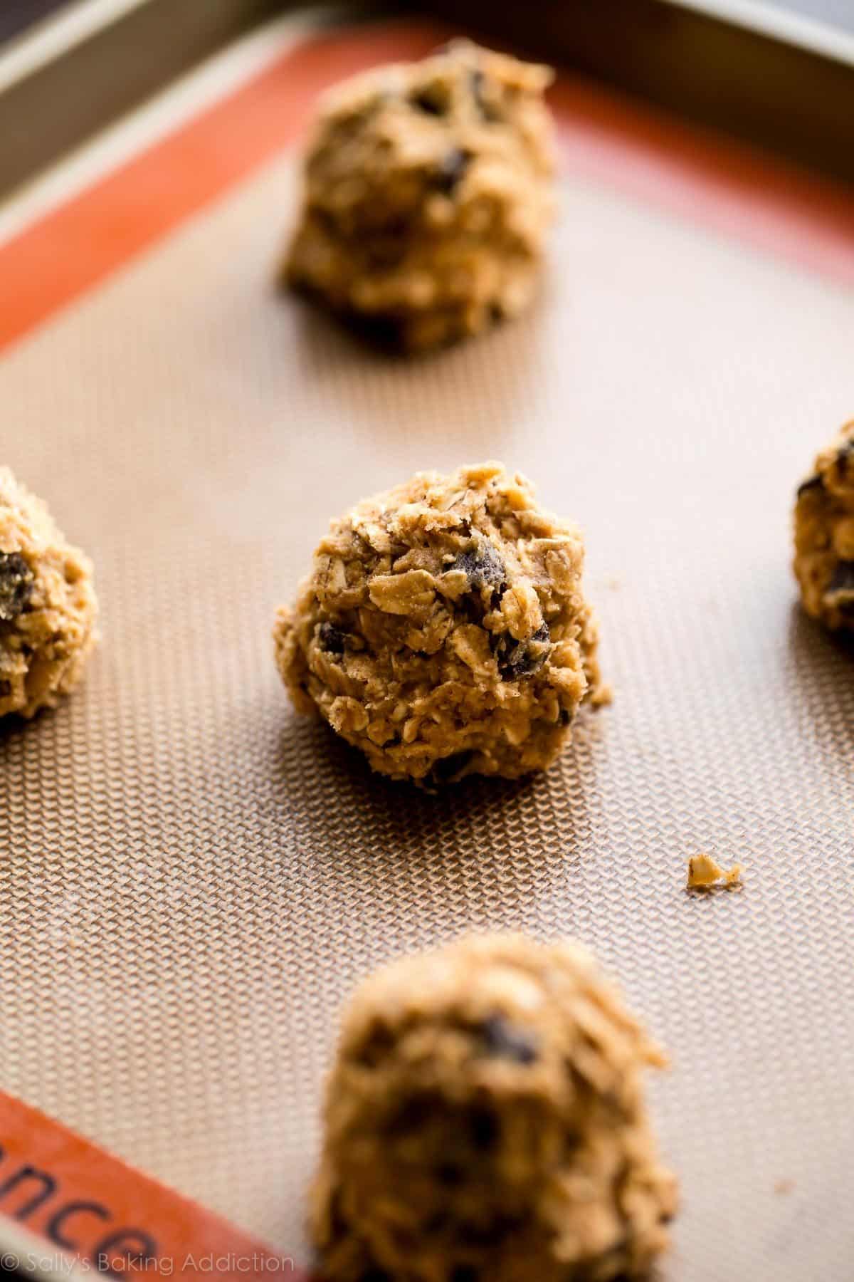 oatmeal chocolate chip cookie dough balls on a silpat mat on a baking sheet