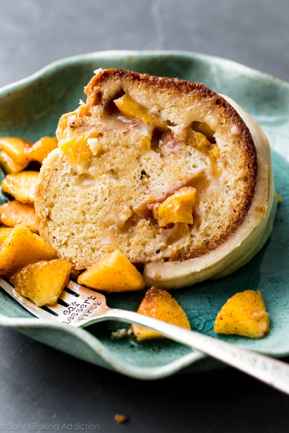 slice of peach bundt cake on a teal plate with a fork