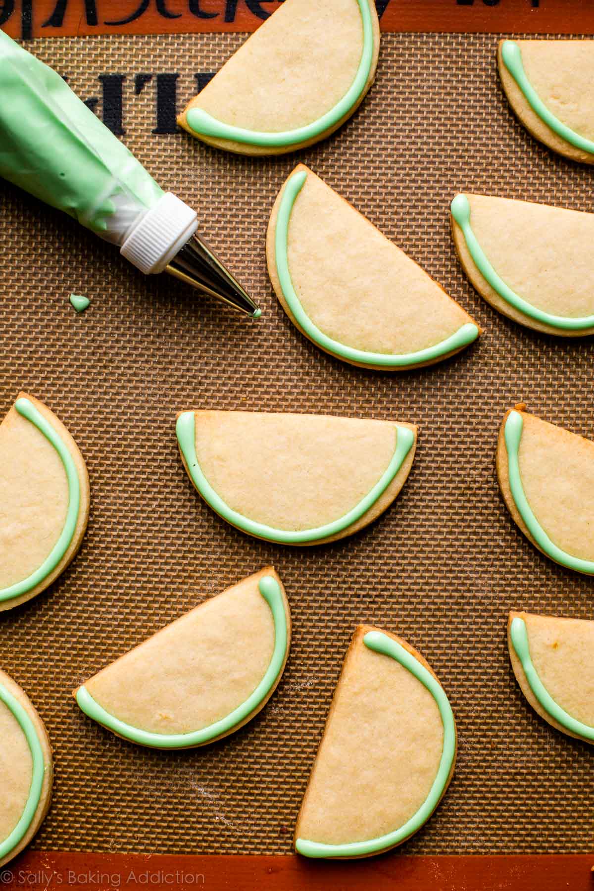 green royal icing piped onto watermelon sugar cookies