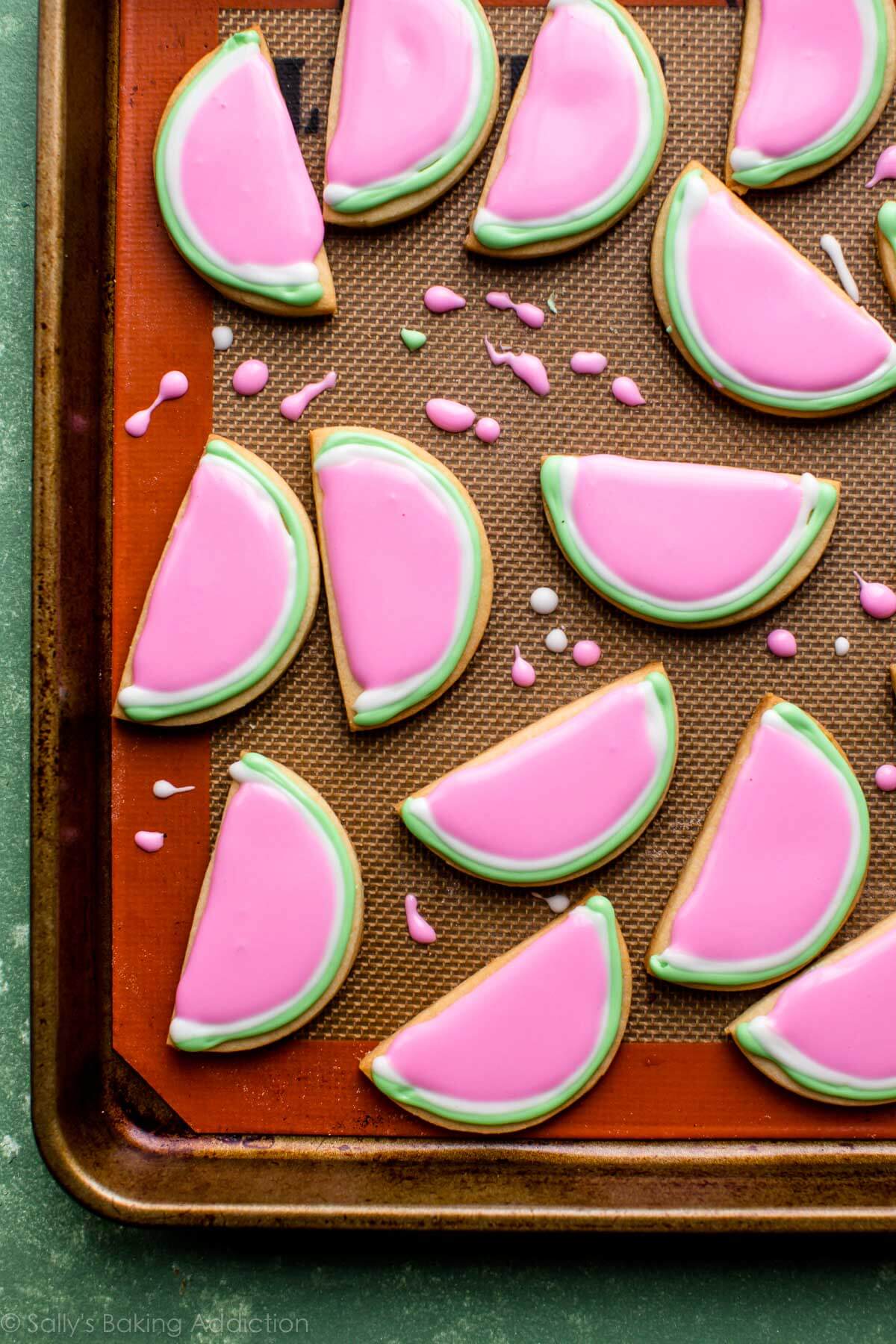 watermelon sugar cookies with green, white, and pink royal icing on a baking sheet