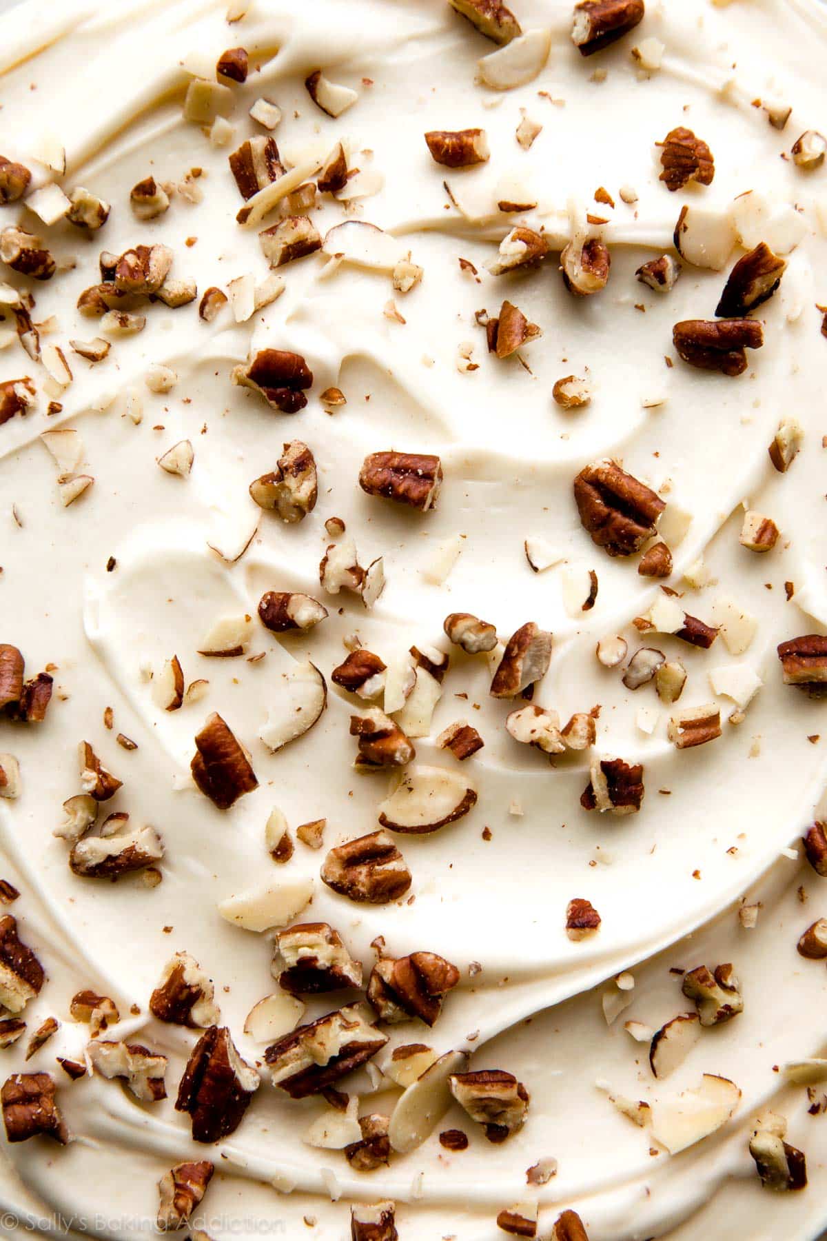 zoomed in image of brown butter cream cheese frosting with chopped pecans on top