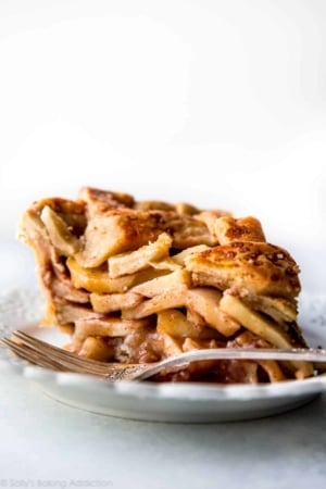slice of deep dish apple pie on white plate with a fork