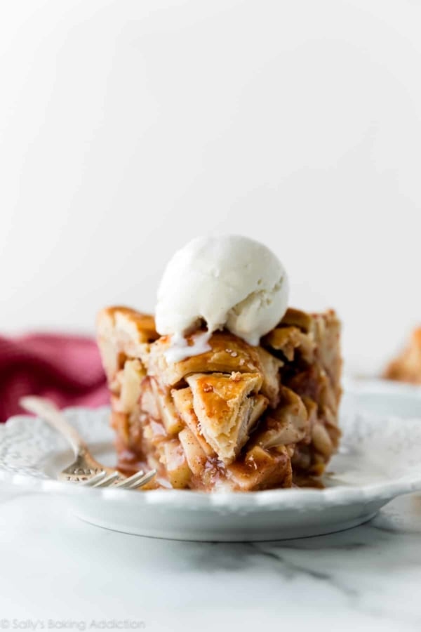 deep dish apple pie slice with vanilla ice cream on white plate