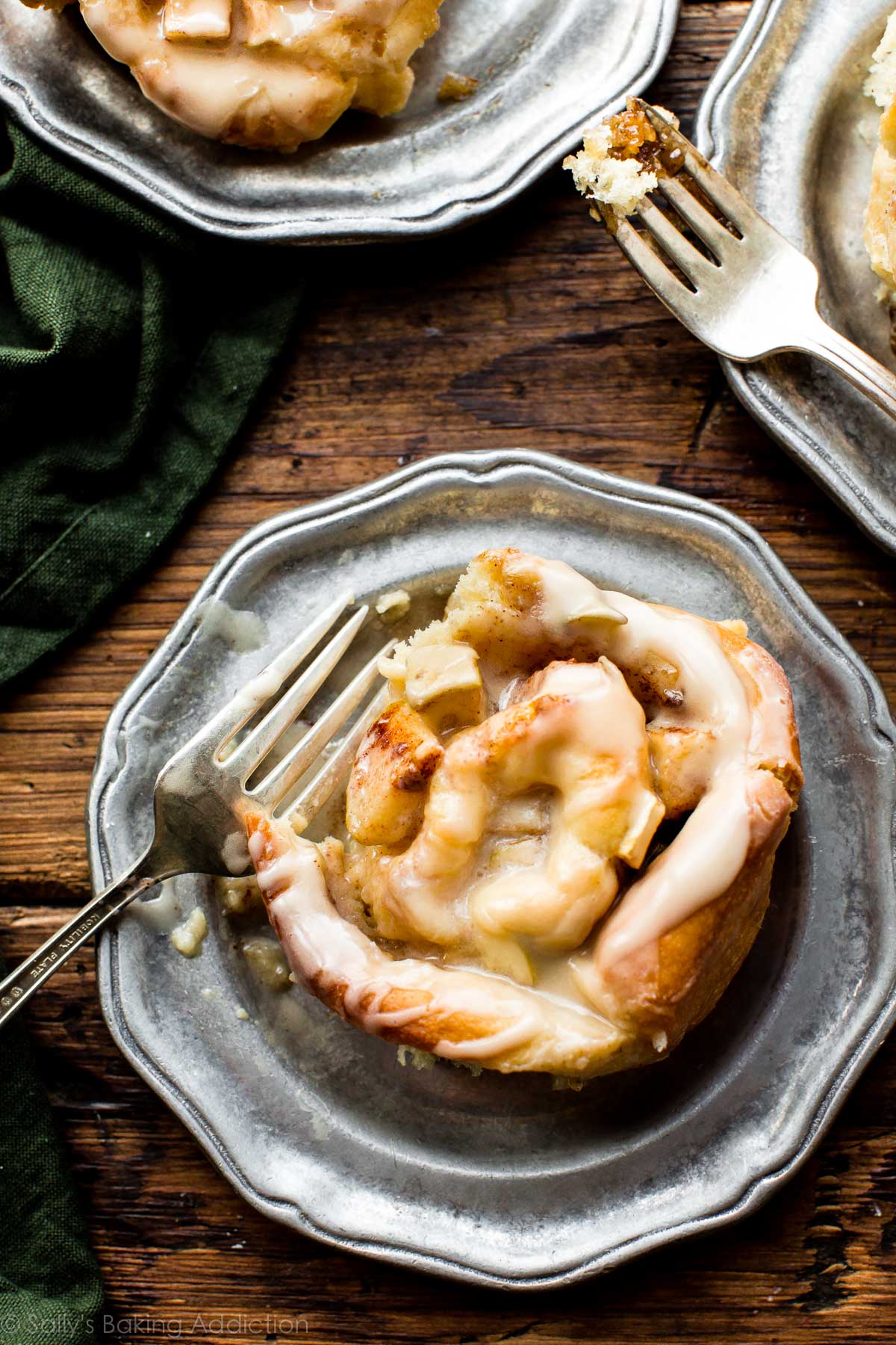 apple cinnamon roll on a silver plate with a fork
