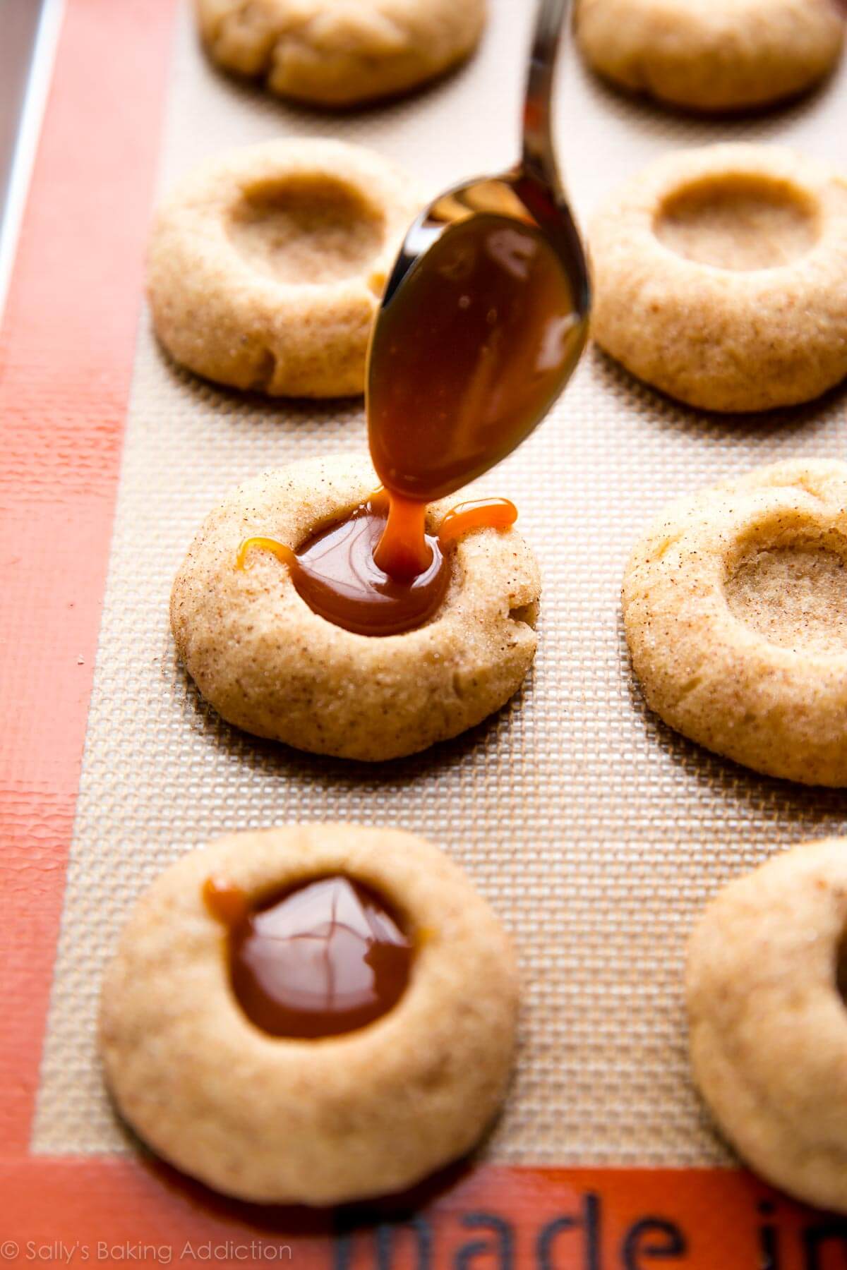 spooning caramel filling into thumbprint cookies