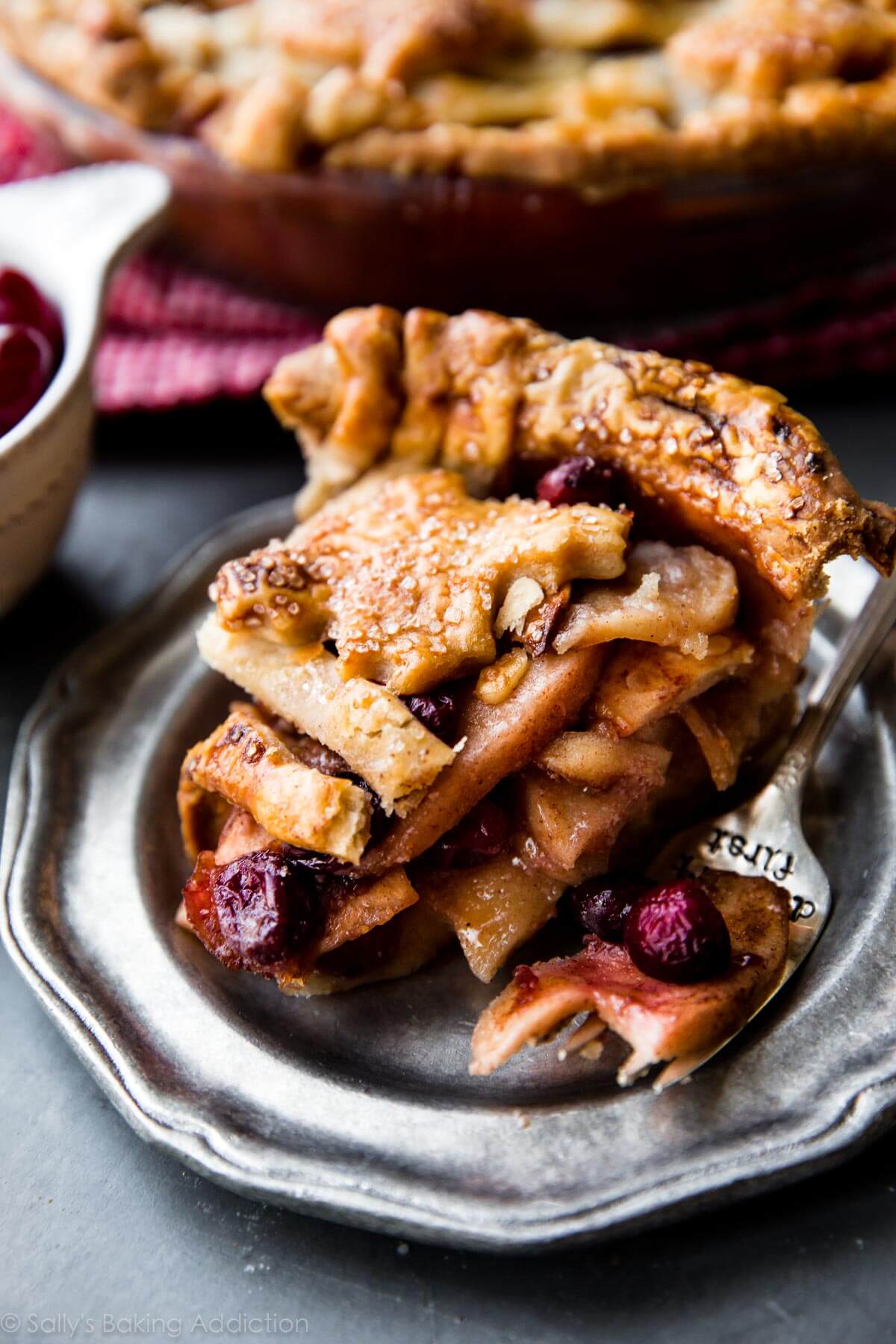 slice of cranberry almond apple pie on a silver plate with a fork