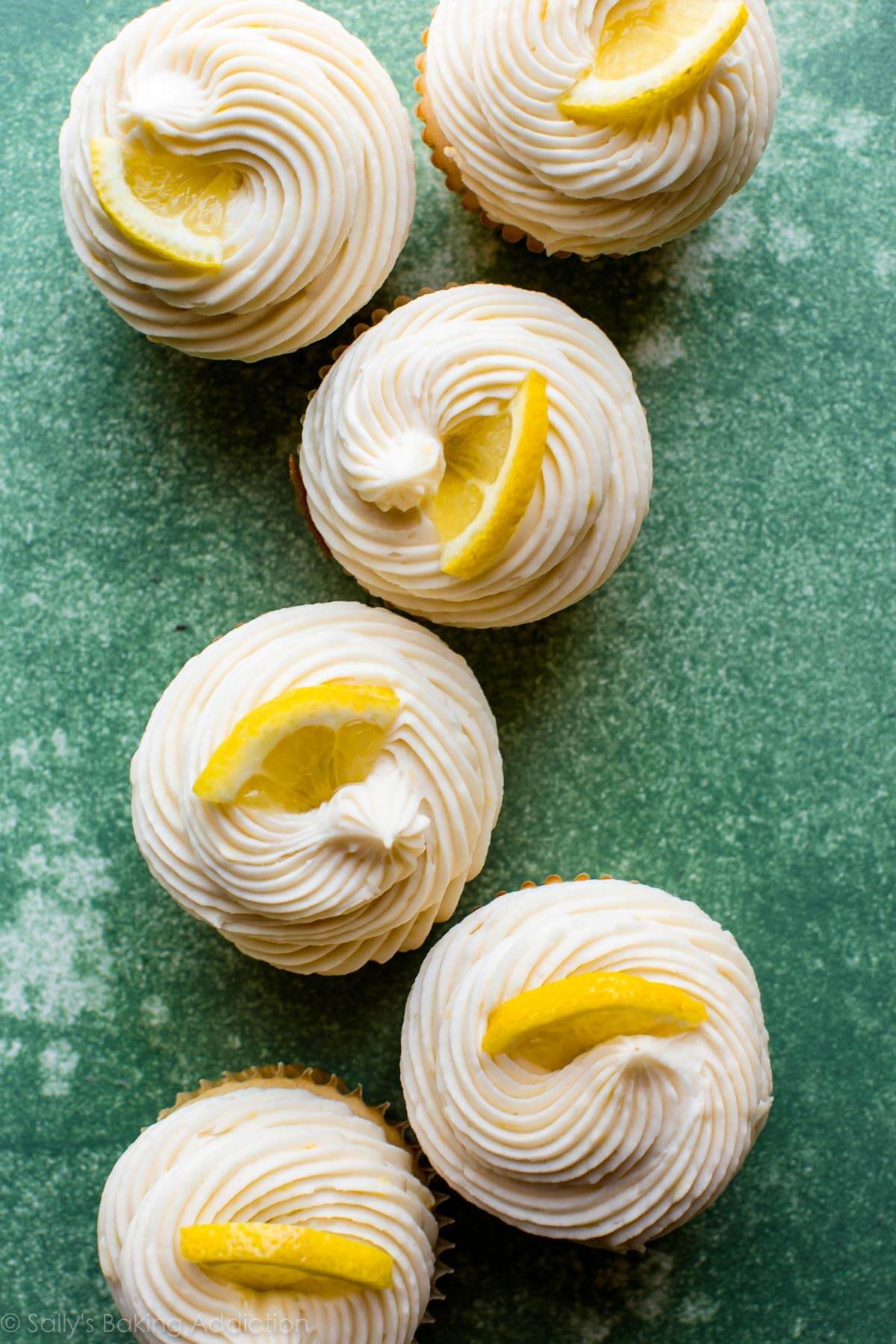 overhead image of lemon buttercream frosting piped onto cupcakes and topped with lemon slices