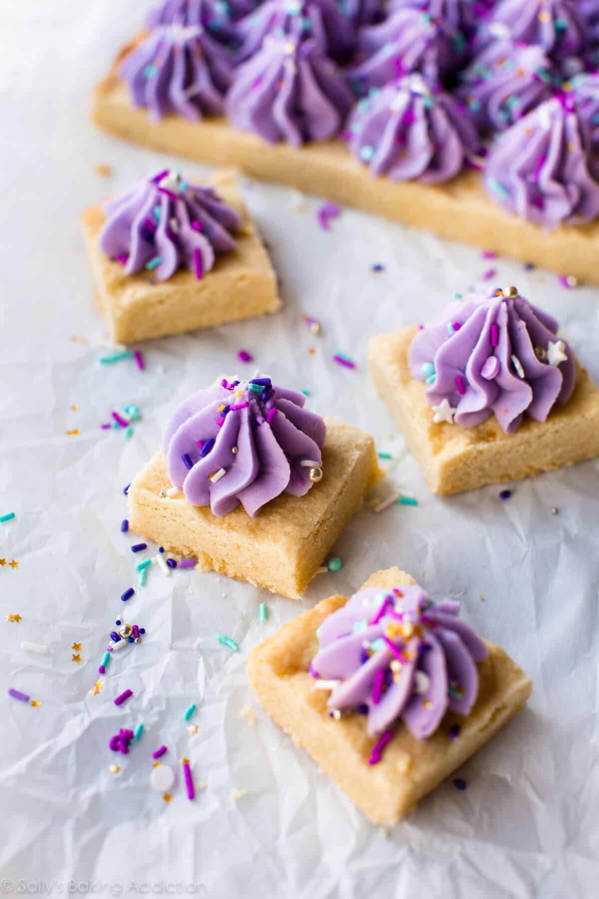 sugar cookie bars with dollops of purple frosting with sprinkles