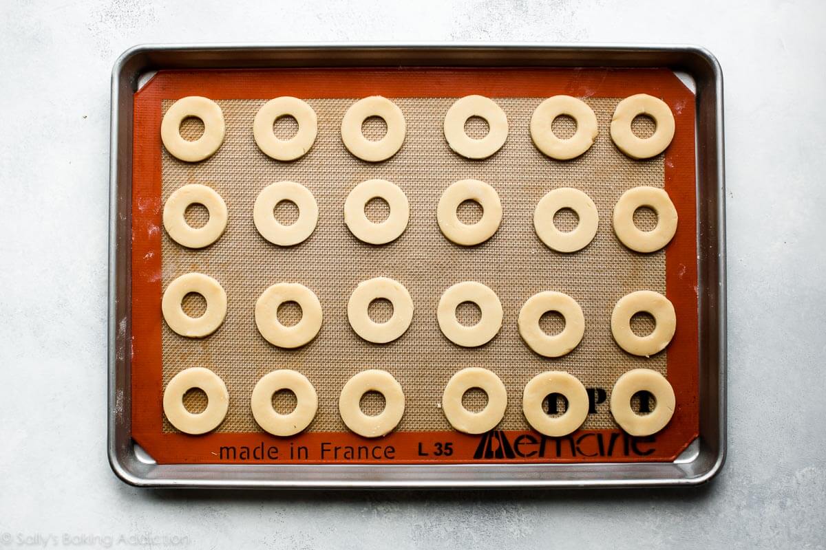 circles of cookie dough with the centers cut out on a baking sheet before baking