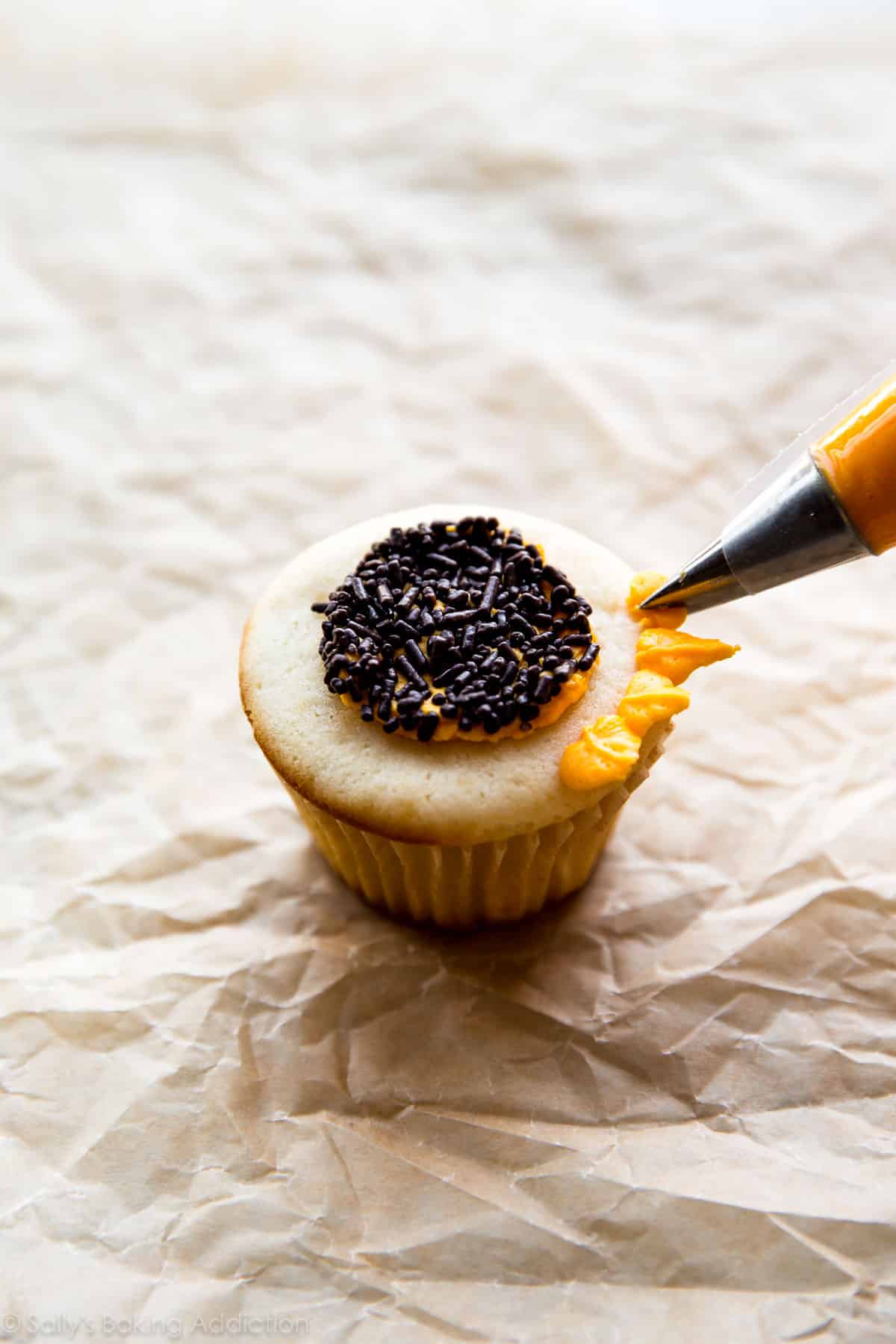 piping sunflower petals onto cupcake with yellow frosting