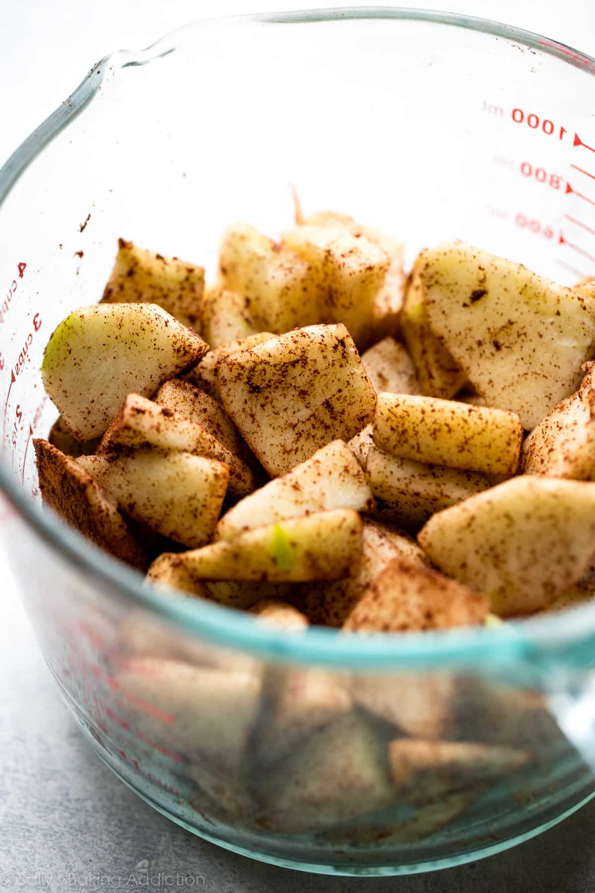 chopped apples and spices in a glass measuring cup