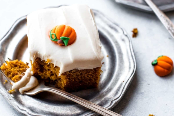 slices of pumpkin cake with cream cheese frosting on silver plates with forks