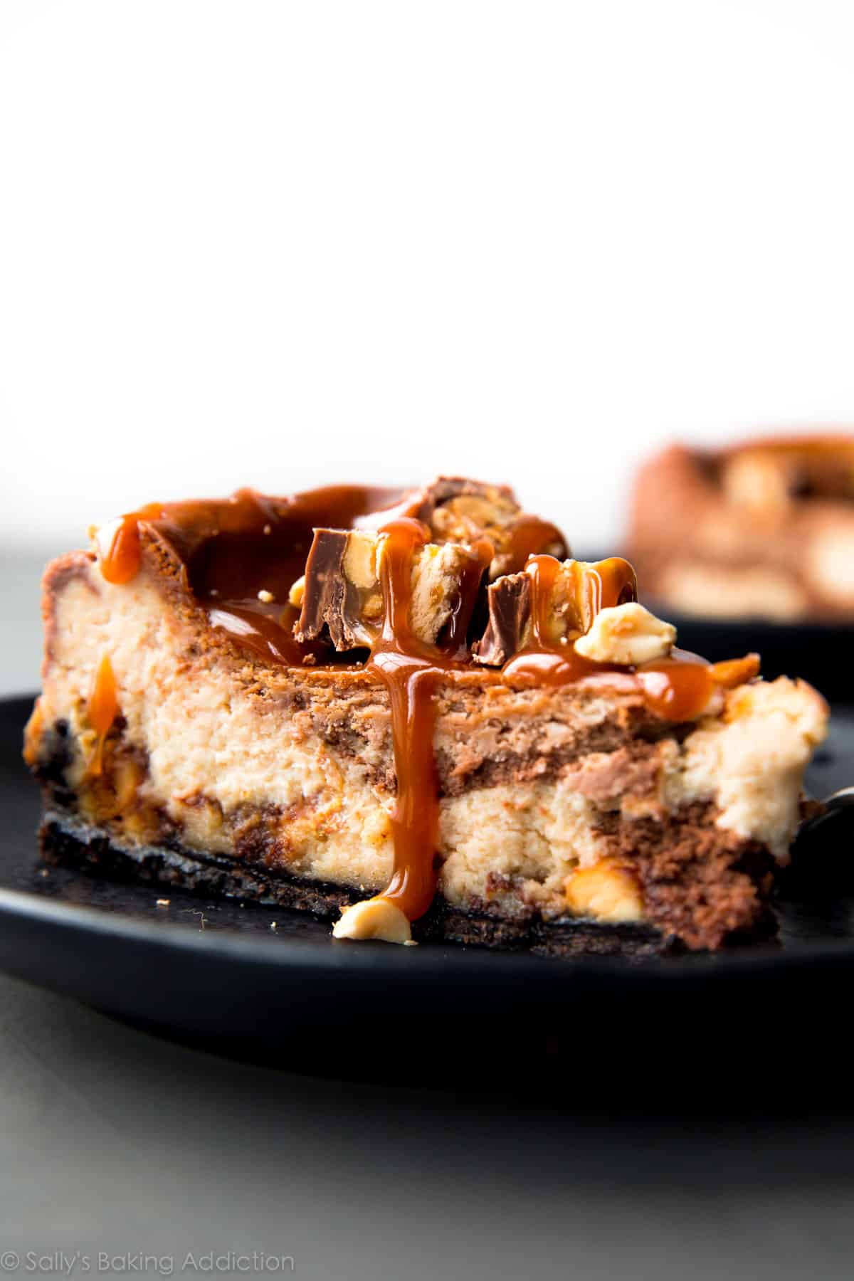 slice of Snickers cheesecake on a black plate