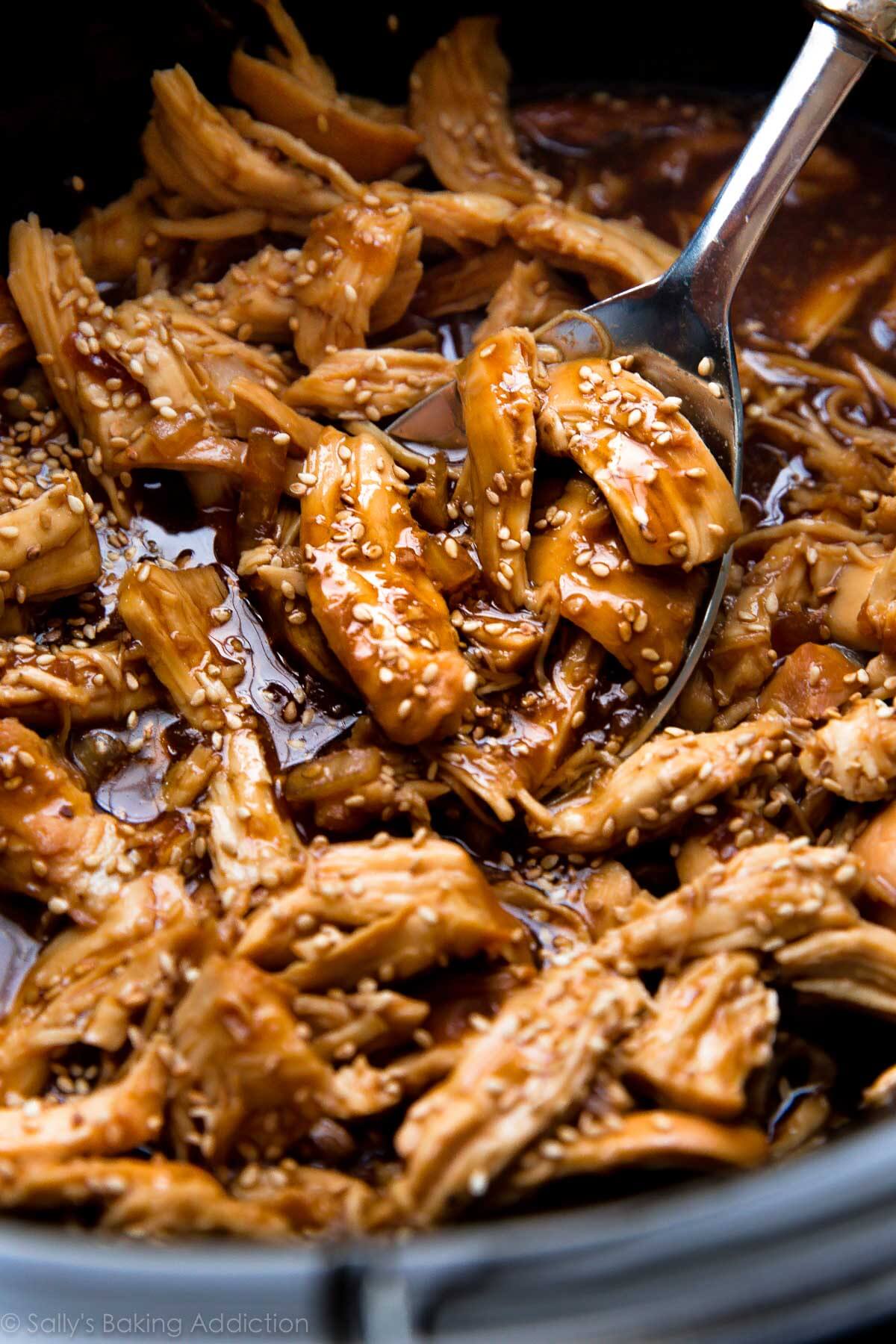 teriyaki chicken in the slow cooker with a metal spoon