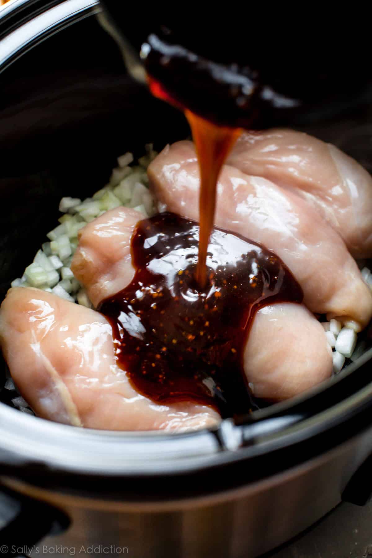 pouring teriyaki sauce onto chicken breasts in a slow cooker