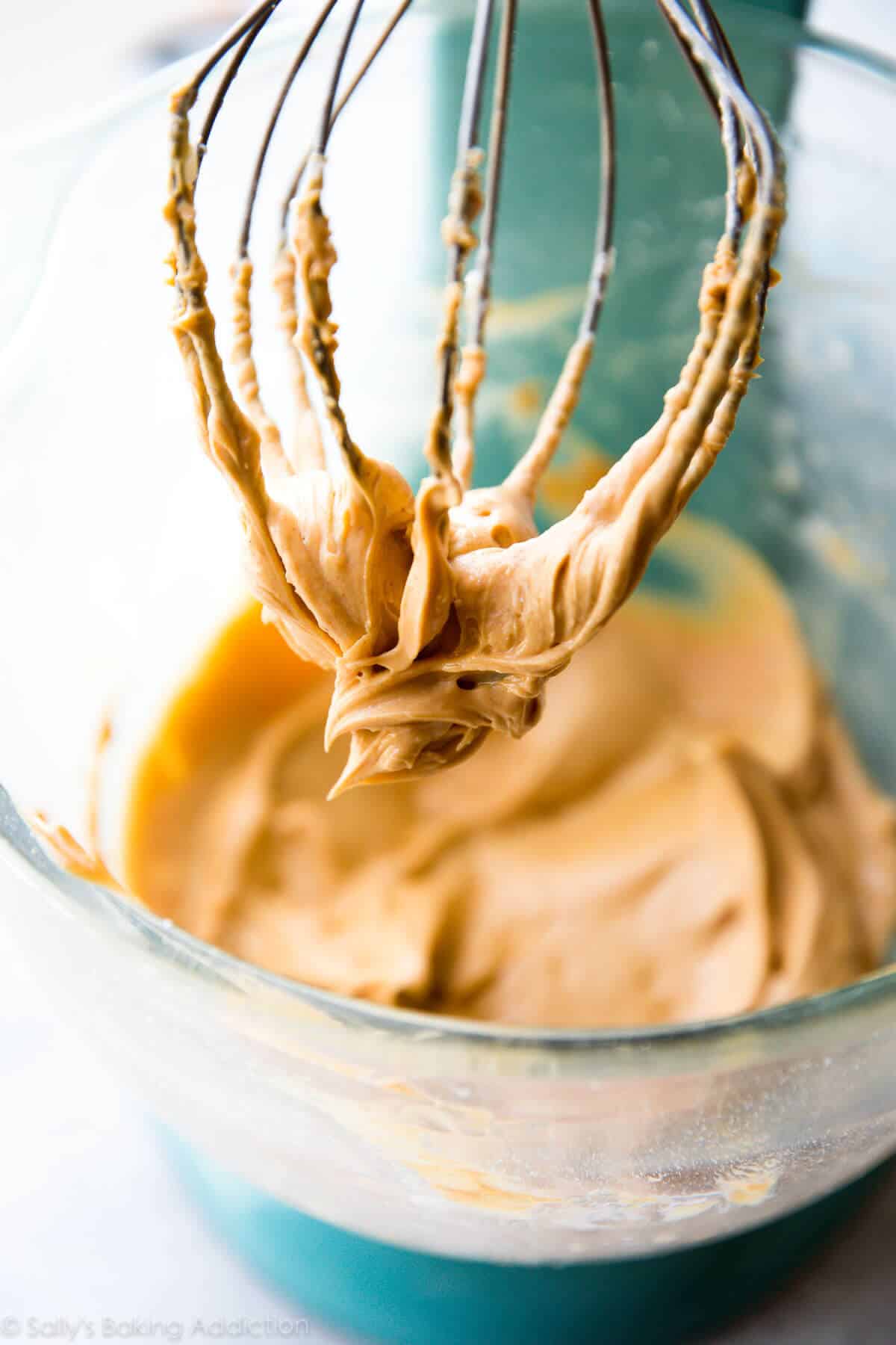 peanut butter frosting in a glass stand mixer bowl with the whisk attachment