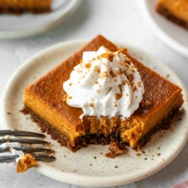 pumpkin pie bar with whipped cream on a plate.