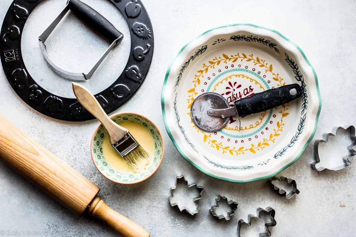 tools for making pie crust including a pie dish, pizza cutter, rolling pin, cookie cutters, pastry cutter, and more