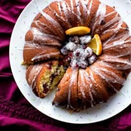 overhead image of cranberry orange bundt cake with sugared cranberries and orange slices in the middle