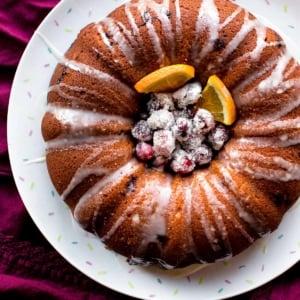 overhead image of cranberry orange bundt cake with sugared cranberries and orange slices in the middle