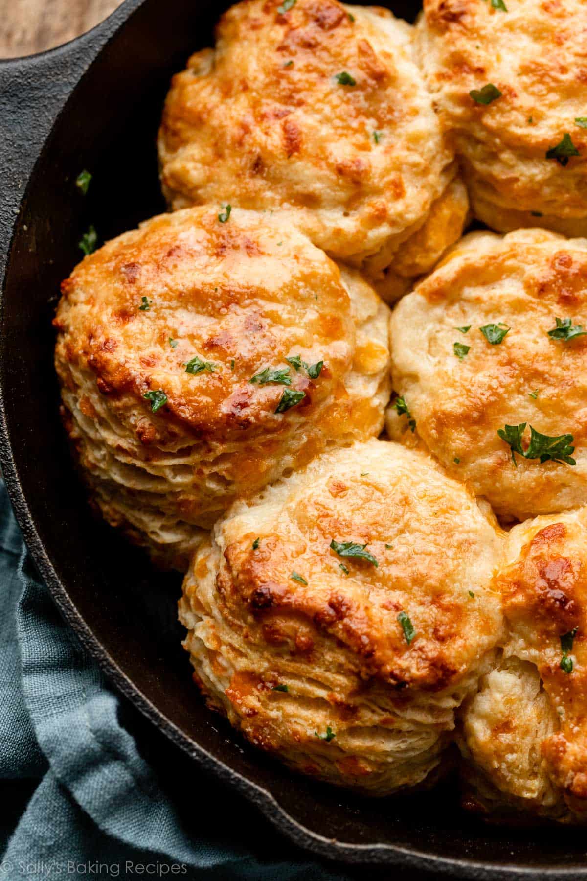 cheddar cheese biscuits with parsley topping in cast iron skillet.