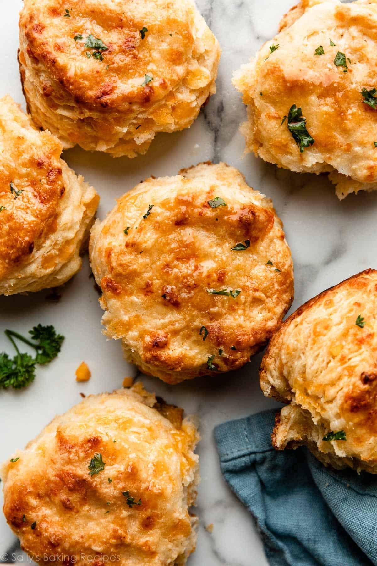 cheddar biscuits with parsley topping on marble counter.