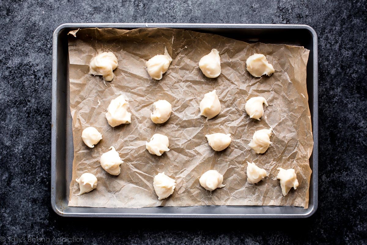 spoonfuls of cream cheese filling on a parchment lined baking sheet