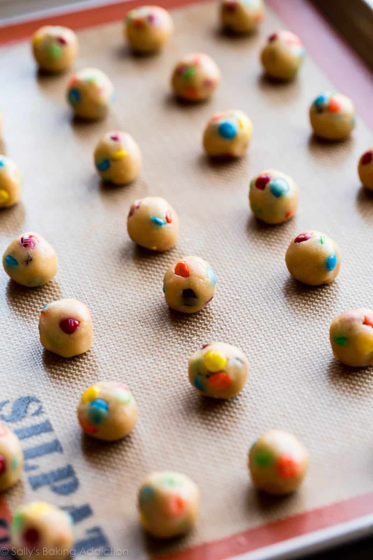 mini M&M cookie dough balls on a baking sheet before baking