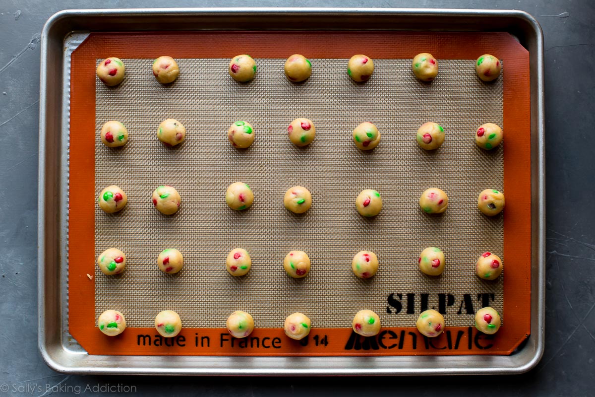 mini M&M cookie dough balls on a baking sheet before baking