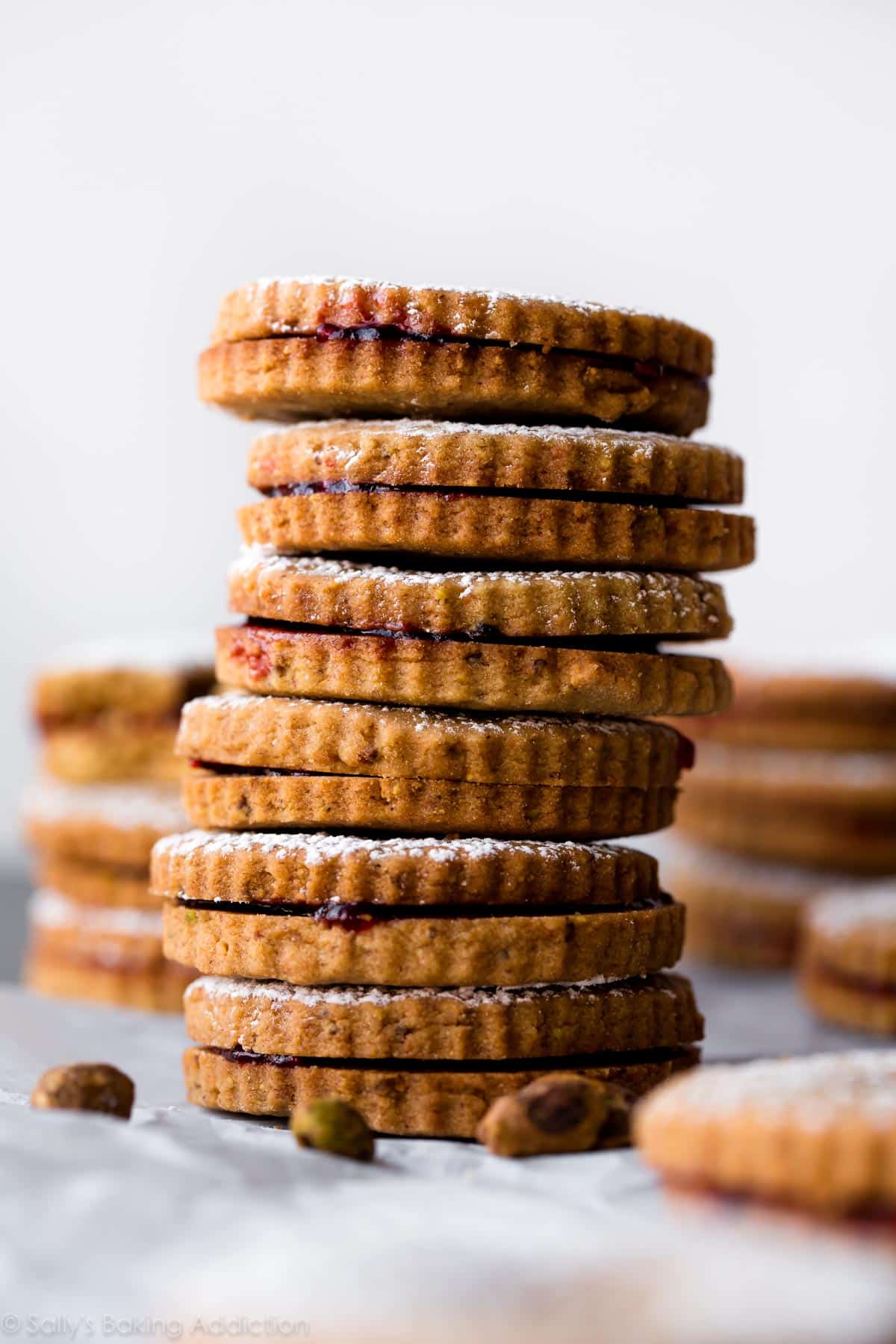 stack of raspberry pistachio linzer cookies