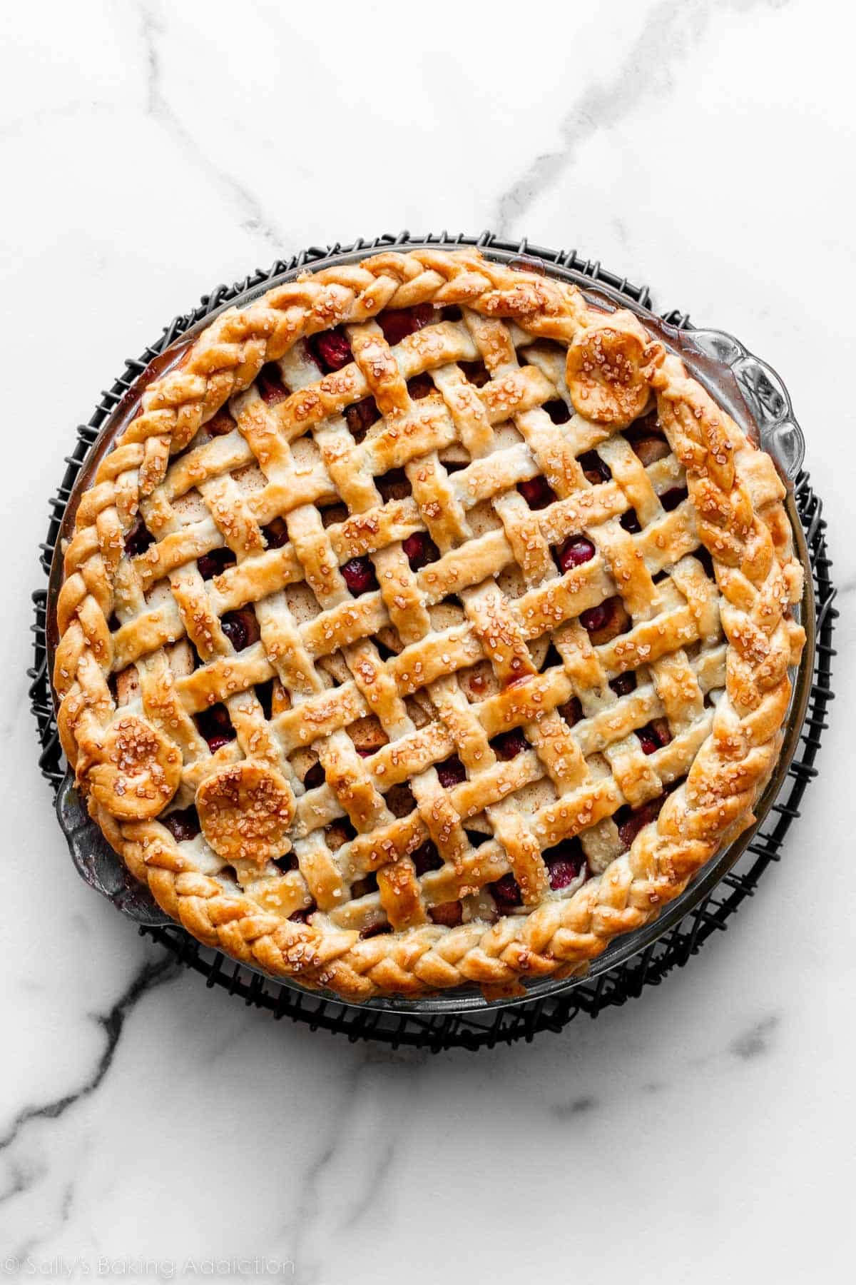 pie with wavy lattice pie dough, braided pie dough edge, and three apple pie crust shapes on top.