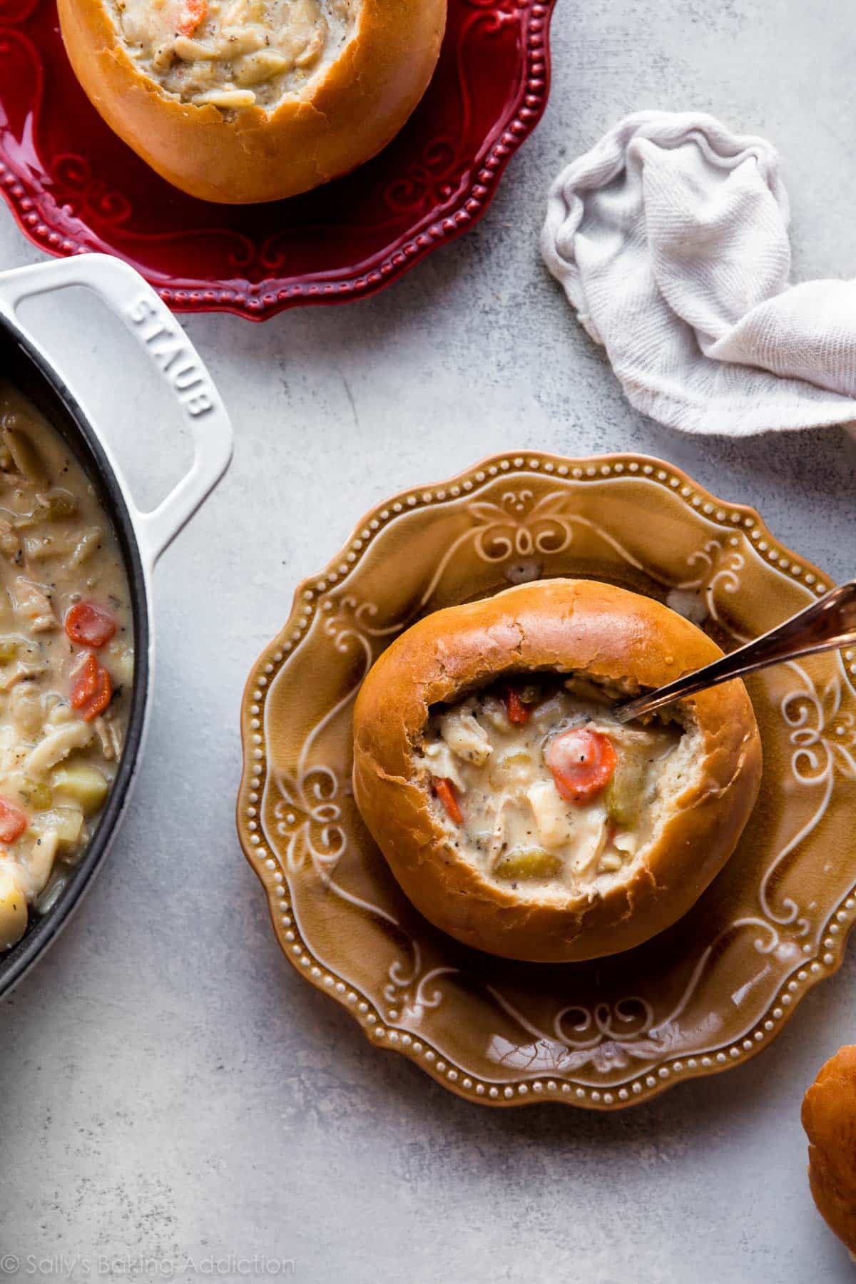 overhead image of bread bowls on plates with chicken noodle soup