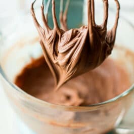 chocolate cream cheese frosting in a glass bowl and on a whisk attachment