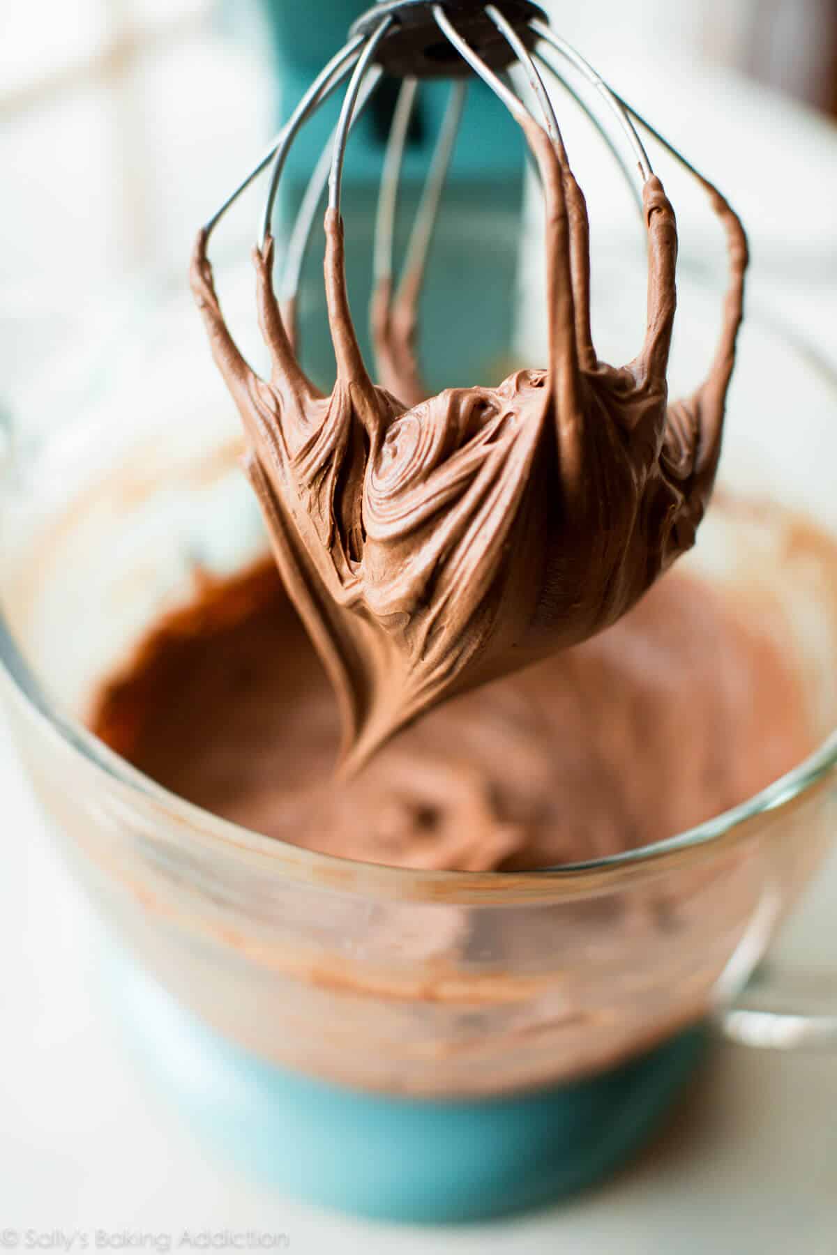chocolate cream cheese frosting in a glass bowl and on a whisk attachment