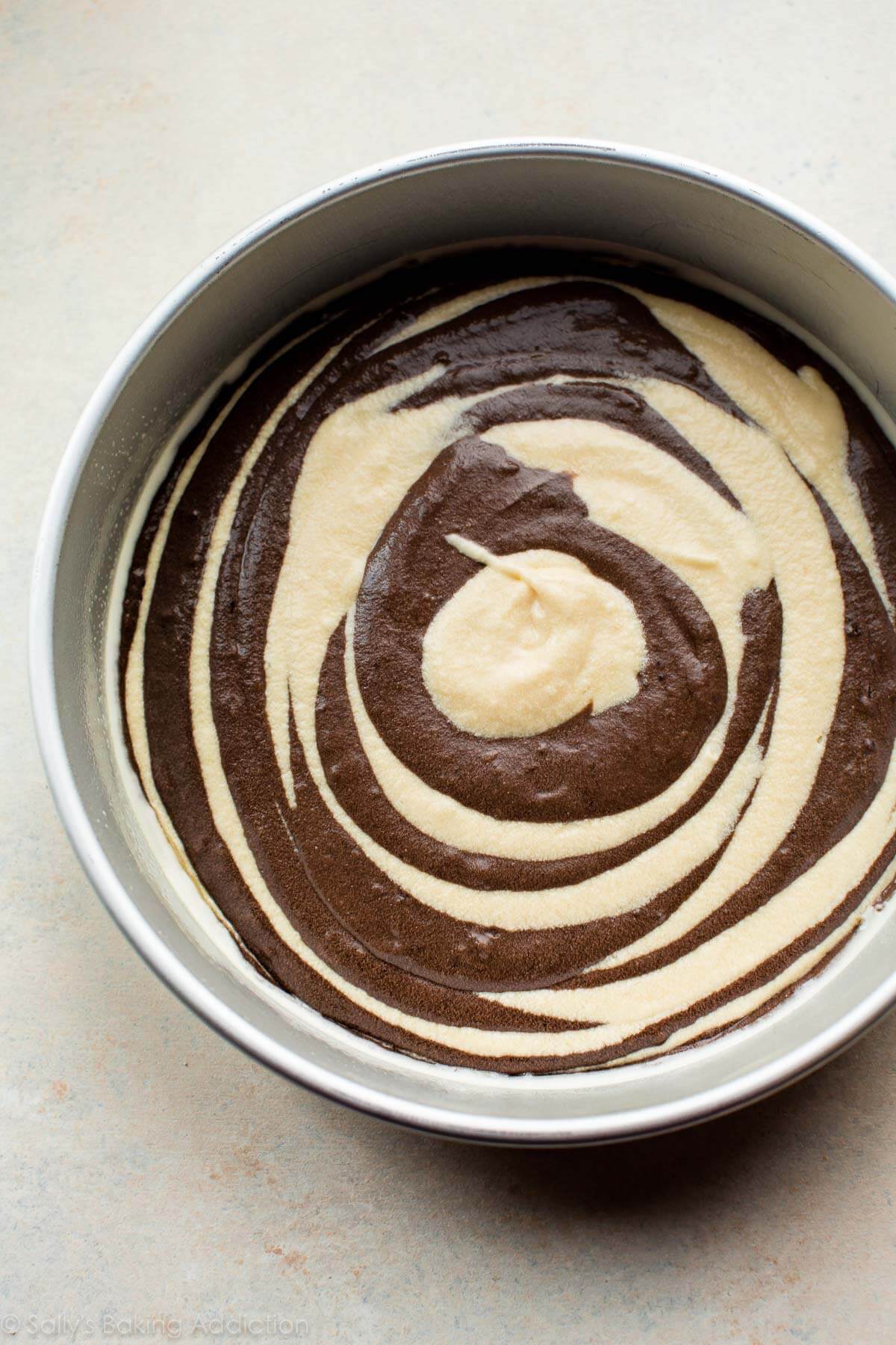 vanilla and chocolate cake batter swirled together in a cake pan before baking