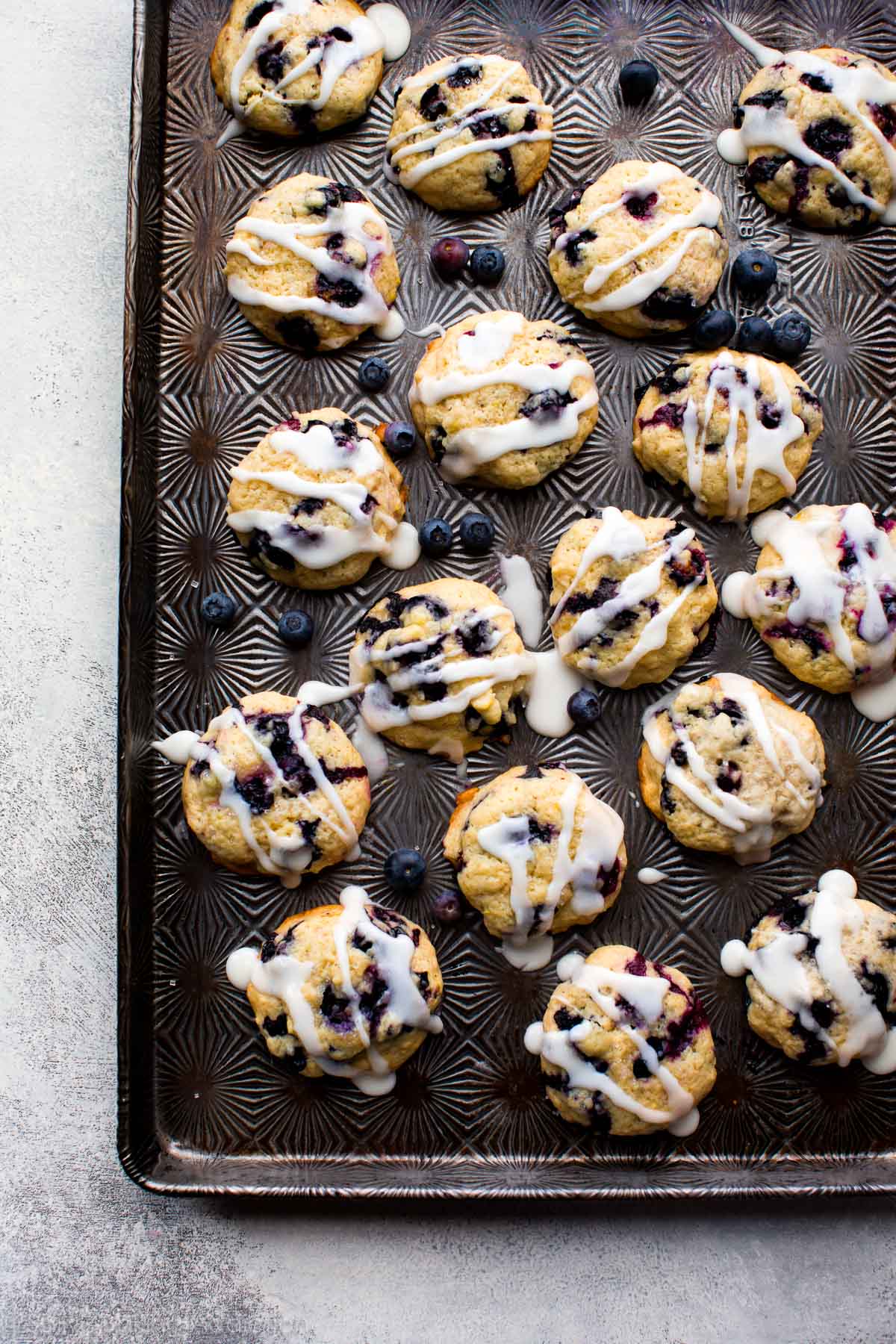 Blueberry muffin cookies with lemon glaze on a baking sheet