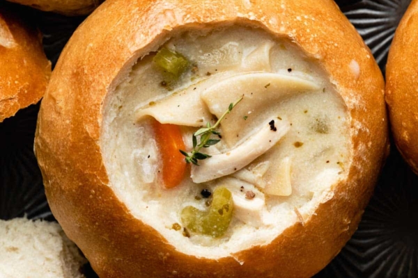 bread bowls on baking sheet filled with chicken noodle soup.