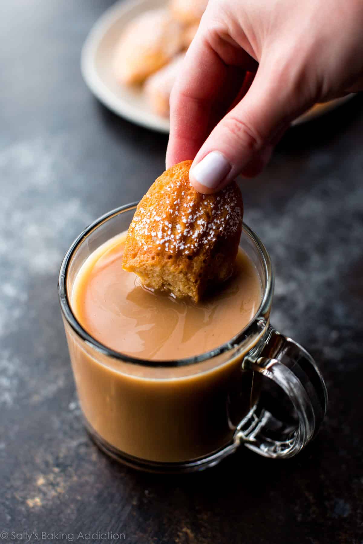 hand dunking a madeleine into a cup of coffee