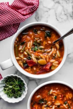 overhead photo of bowls of tomato and broth-based minestrone soup with orzo pasta.