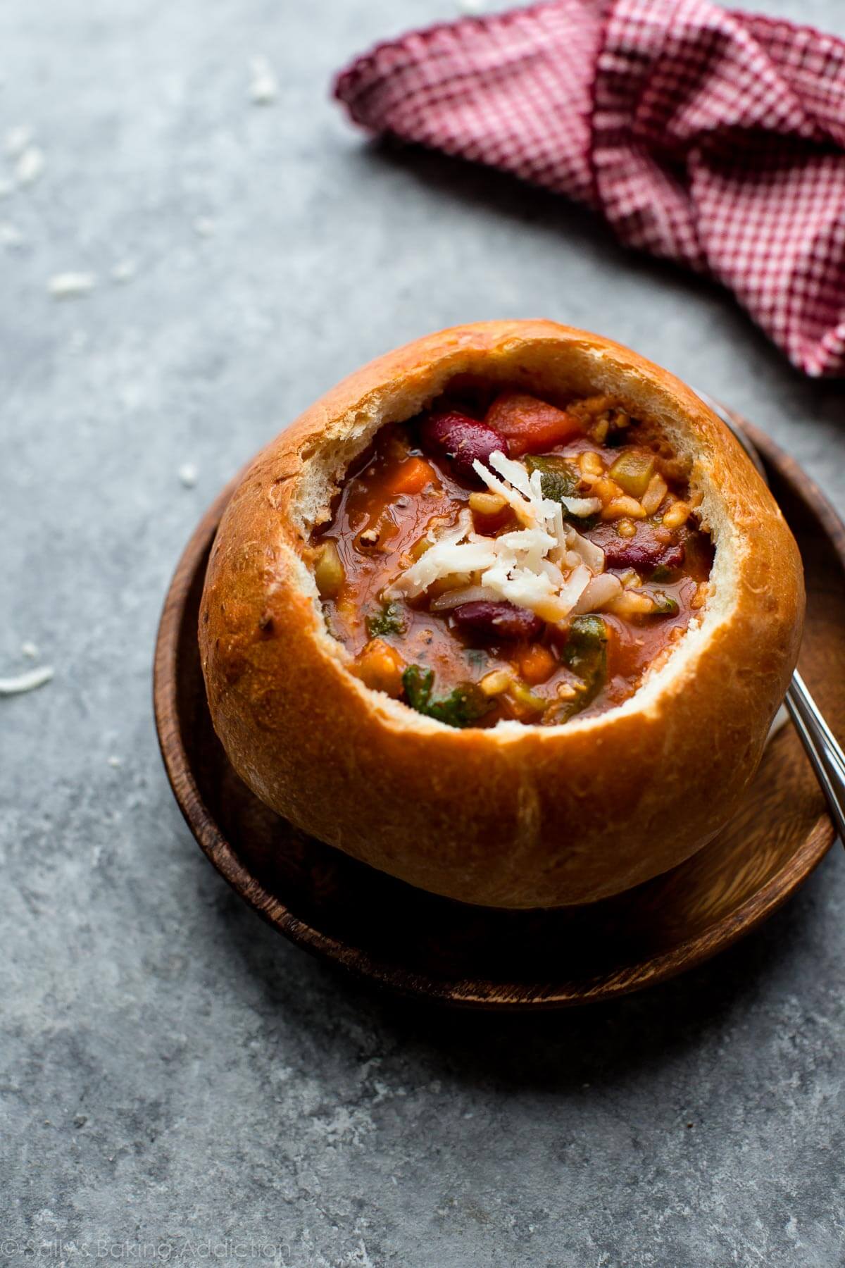 Minestrone soup in a bread bowl on a wood plate