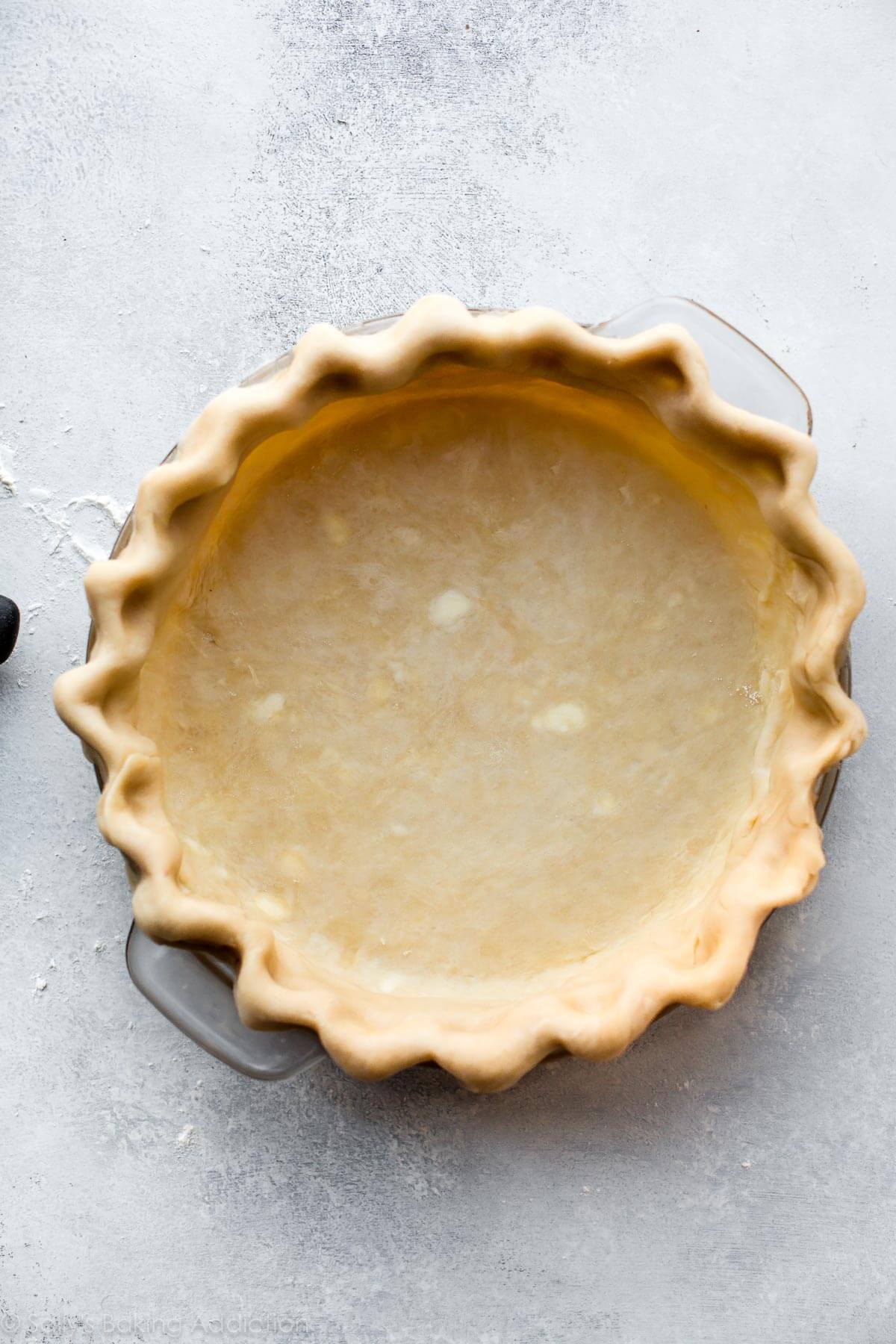 fluted pie dough in a glass pie dish before baking