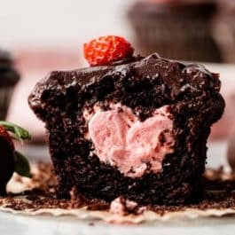 close-up of chocolate cupcake topped with chocolate ganache and filled with strawberry buttercream.