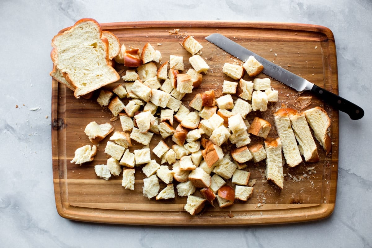 Cubed challah bread on a wood cutting board